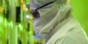 person in clean room wearing clean suit. Neon green background